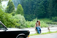 一对年轻夫妇坐在河边，在郁郁葱葱的森林中享受轻松时光