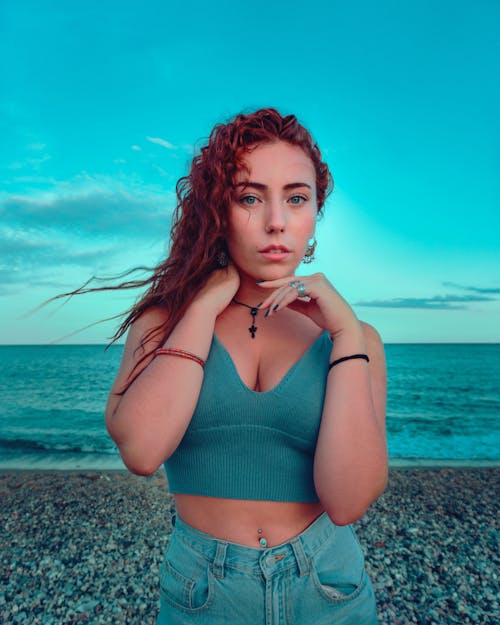 red-haired girl with blue eyes posing on the beach