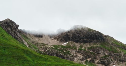 Free Majestic view of a green and rocky mountain with mist and clouds enveloping its peak. Stock Photo