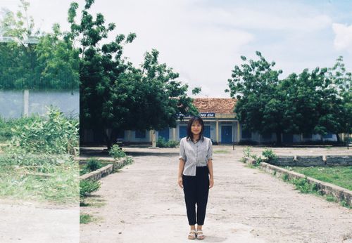 Free Asian woman smiling and standing in a sunny courtyard under a blue sky. Stock Photo