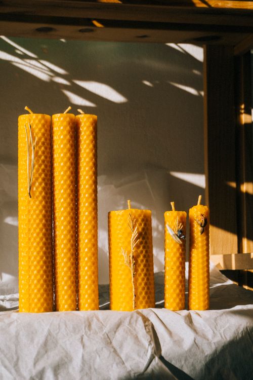 Free Vertical shot of natural beeswax candles casting shadows on a table. Stock Photo