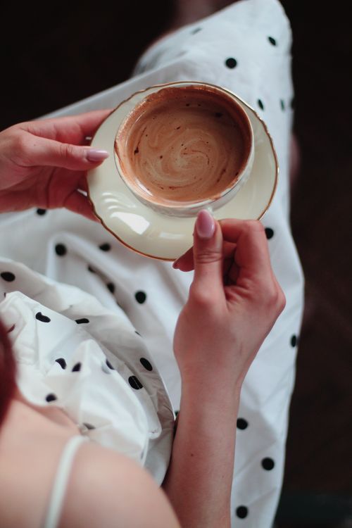 Free Top view of a woman holding a coffee cup, dressed in a polka-dot outfit. Stock Photo