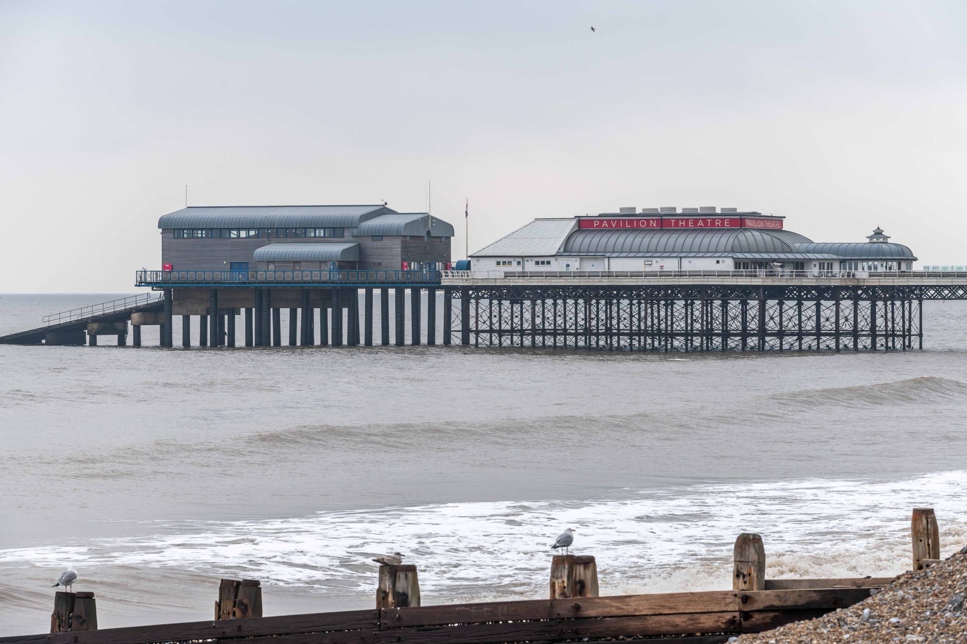 Cromer pier stretching out over the North Sea on a clear day, with the Norfolk coastline behind