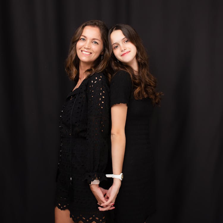 Mother And Daughter In Black Dresses Posing Together