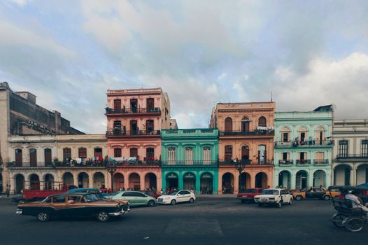 A vibrant street scene depicting colorful colonial buildings and classic cars in Havana, Cuba.