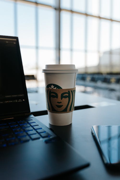 Free Café Starbucks com Notebook e celular no Aeroporto. Stock Photo