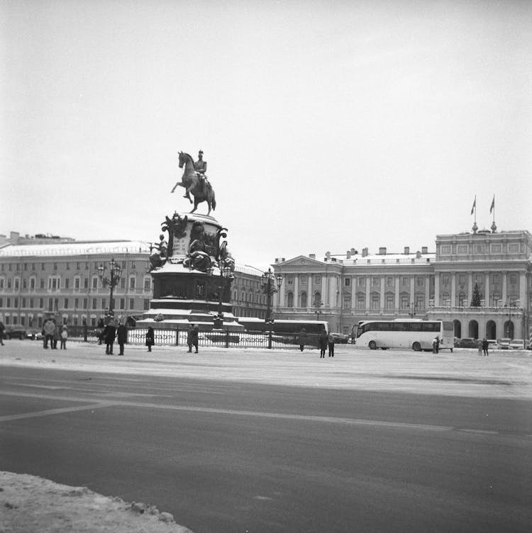 Grayscale Photo Of Man Riding Horse Statue In Front Of A Building