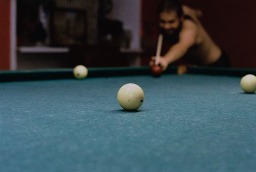 Free A man aiming a cue stick on a billiard table, capturing focus and precision. Stock Photo