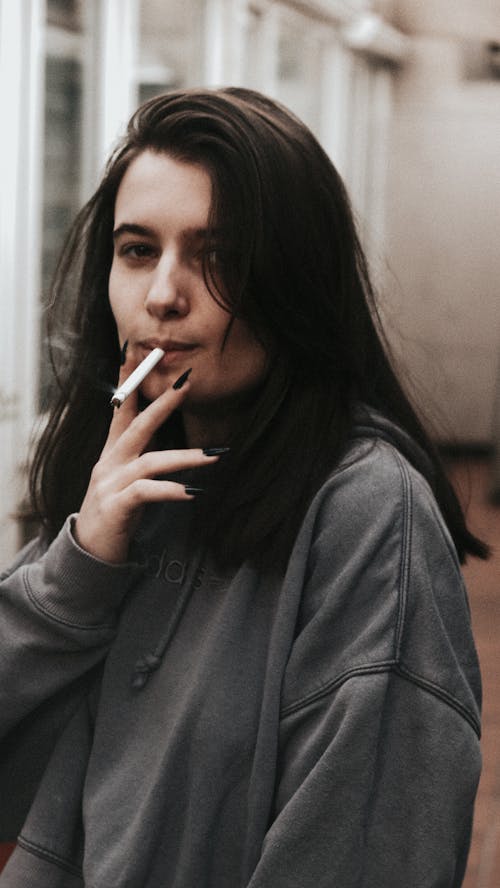 Woman in Gray Hoodie Smoking Cigarette