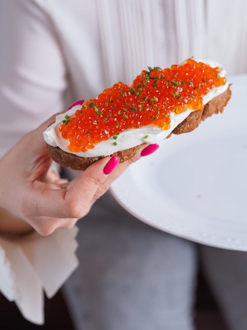A Person Holding a Bread with Red Caviar