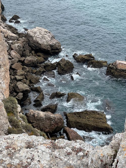 Free Dramatic high-angle view of rocky cliffs meeting the ocean waves, showcasing natural coastal beauty. Stock Photo