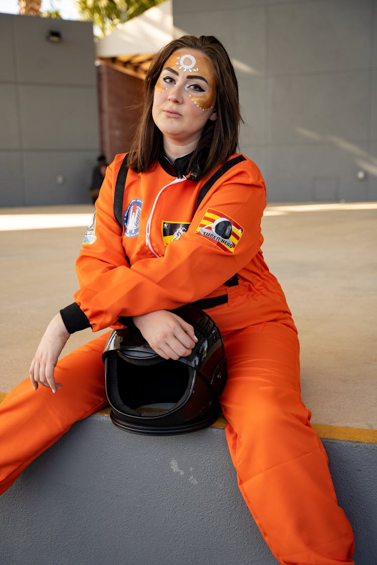 Woman In Orange Work Uniform Sitting In Ground