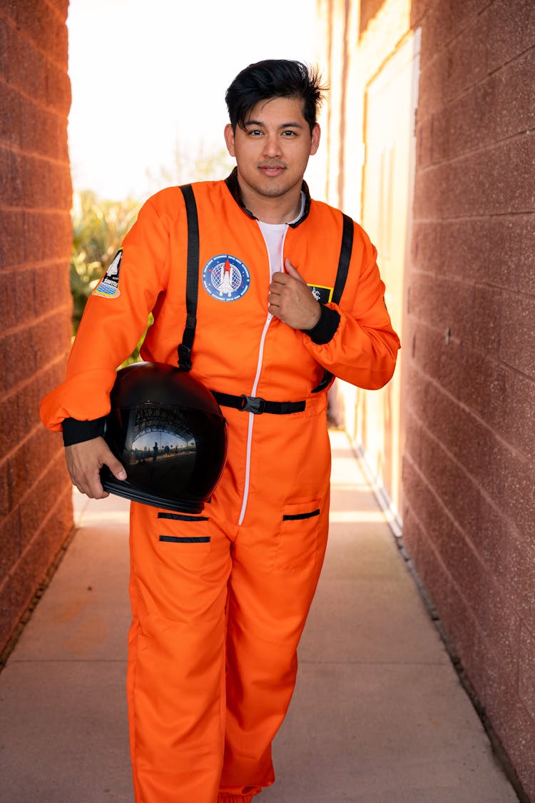 Man In Orange Work Uniform Holding Helmet