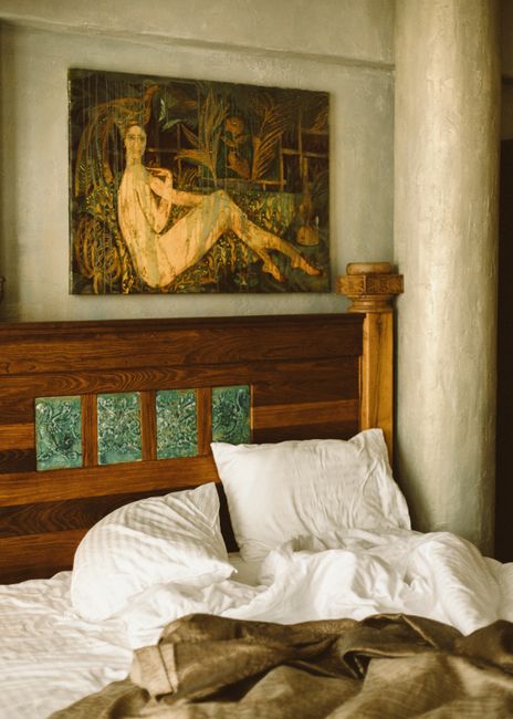 A charming hotel room with a wooden bed and an artistic painting above, offering a cozy atmosphere.