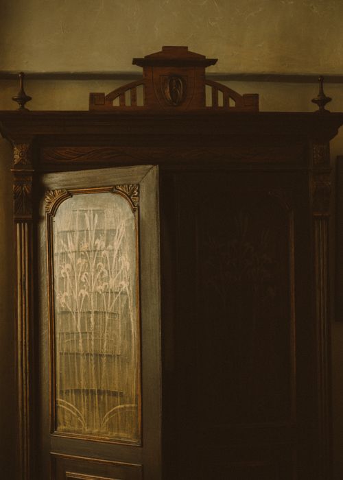 Free Close-up of a vintage wooden cabinet with ornate carvings, lit softly for an antique ambiance. Stock Photo
