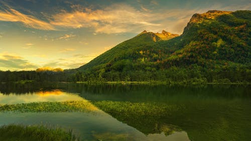 Free Green Mountains near Calm Lake during Sunrise Stock Photo