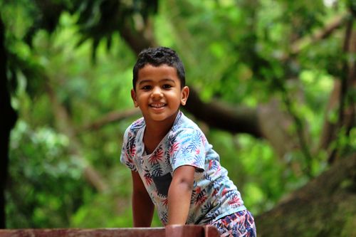 Free Joyful child smiling while playing outdoors in a lush green park. Stock Photo