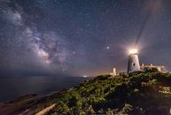 White Lighthouse Near Body of Water during Night Time