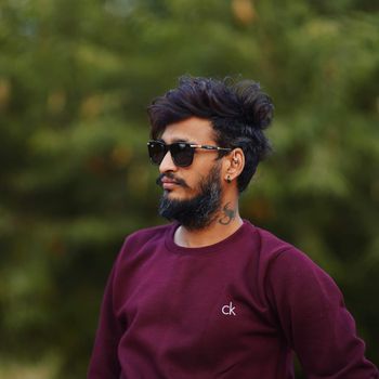 Stylish man with beard and sunglasses casually posing outdoors in Pune, India.