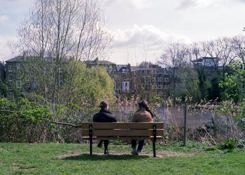 Back View of Two People Sitting on Wooden Bench