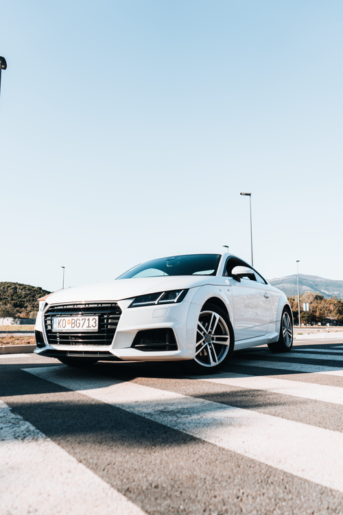 Free Low angle view of a white car parked on a crosswalk under a clear blue sky in Tivat, Montenegro. Stock Photo