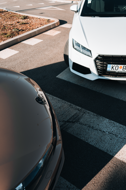 Free Two cars at a crosswalk in Tivat, Montenegro, showcasing urban transport and road markings. Stock Photo