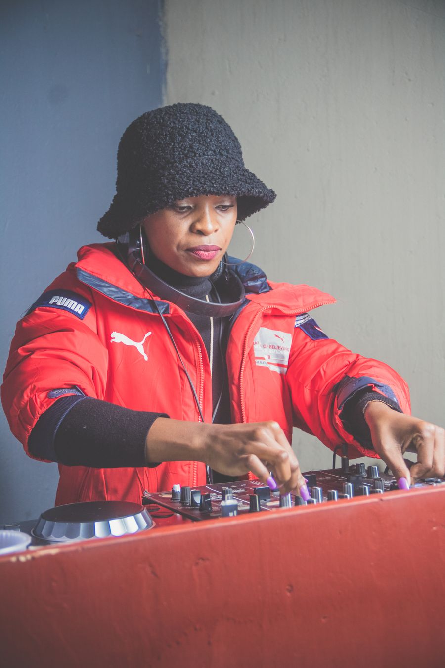 A Black woman DJ in a red coat at the mixer