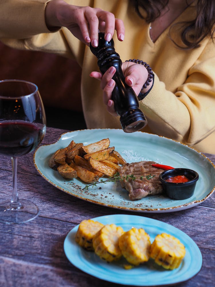 A Person Seasoning A Steak