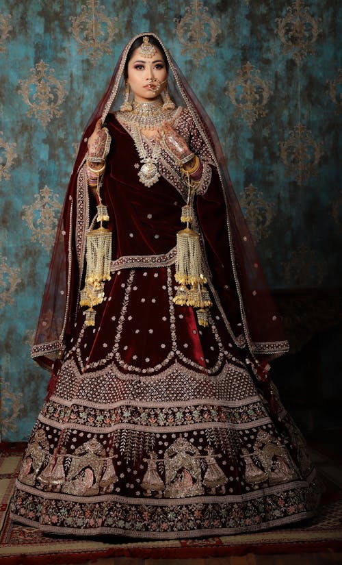 Woman Wearing a Maroon Sari Standing on a Carpet