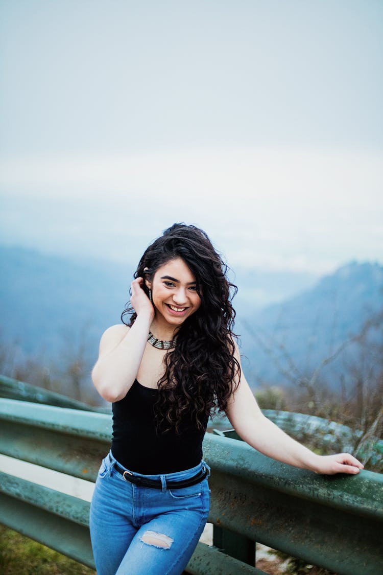 Smiling Cute Girl With Long Black Hair Standing At Road Railing