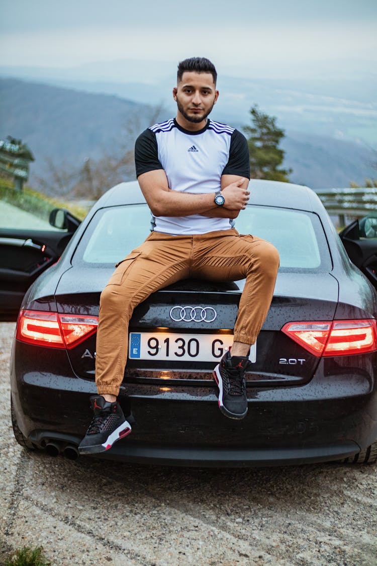 Man Sitting On The Trunk Of A Black Car