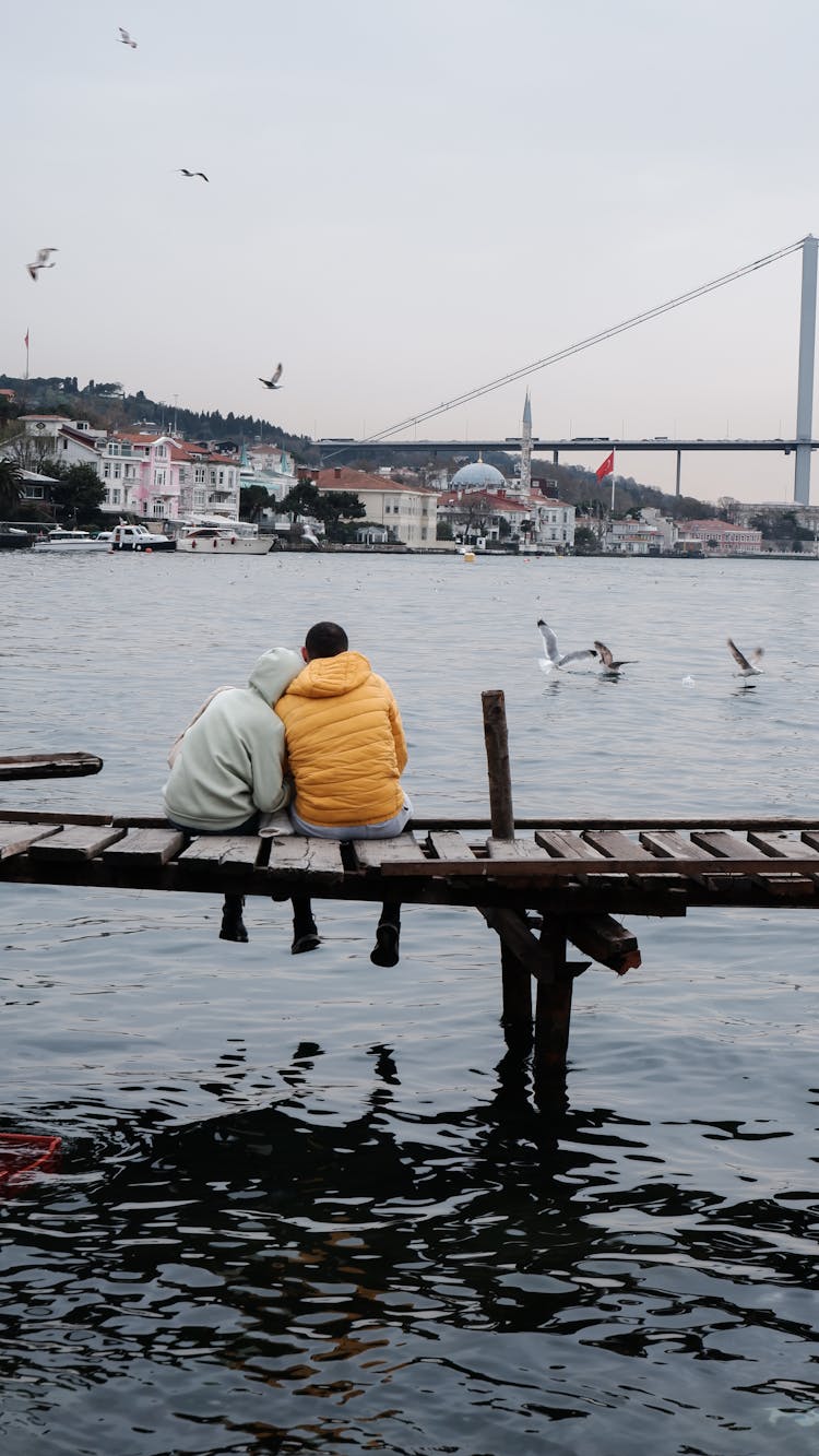 Couple Sitting On Brown Wooden Dock