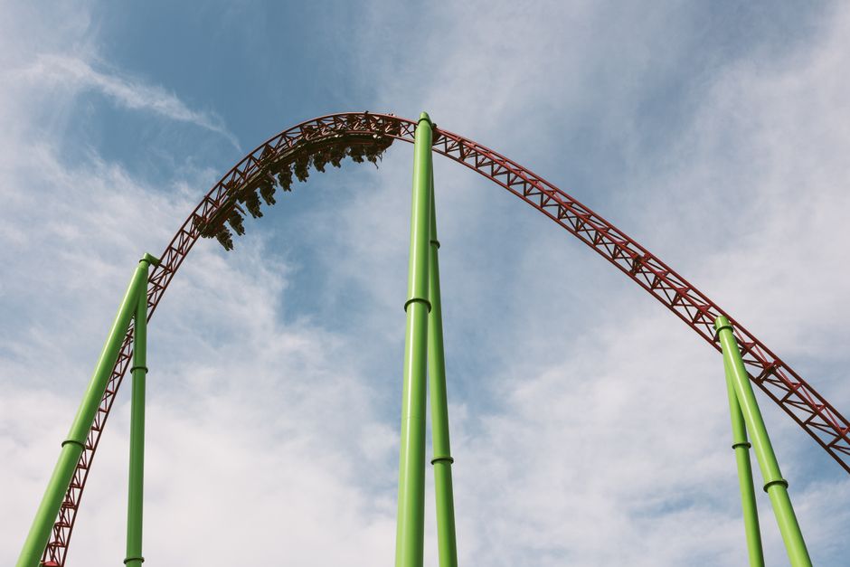 Experience the excitement of a towering steel roller coaster against a clear blue sky.