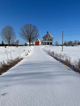 Idyllic snowy scene featuring a country house and frosty landscape under a clear blue sky.