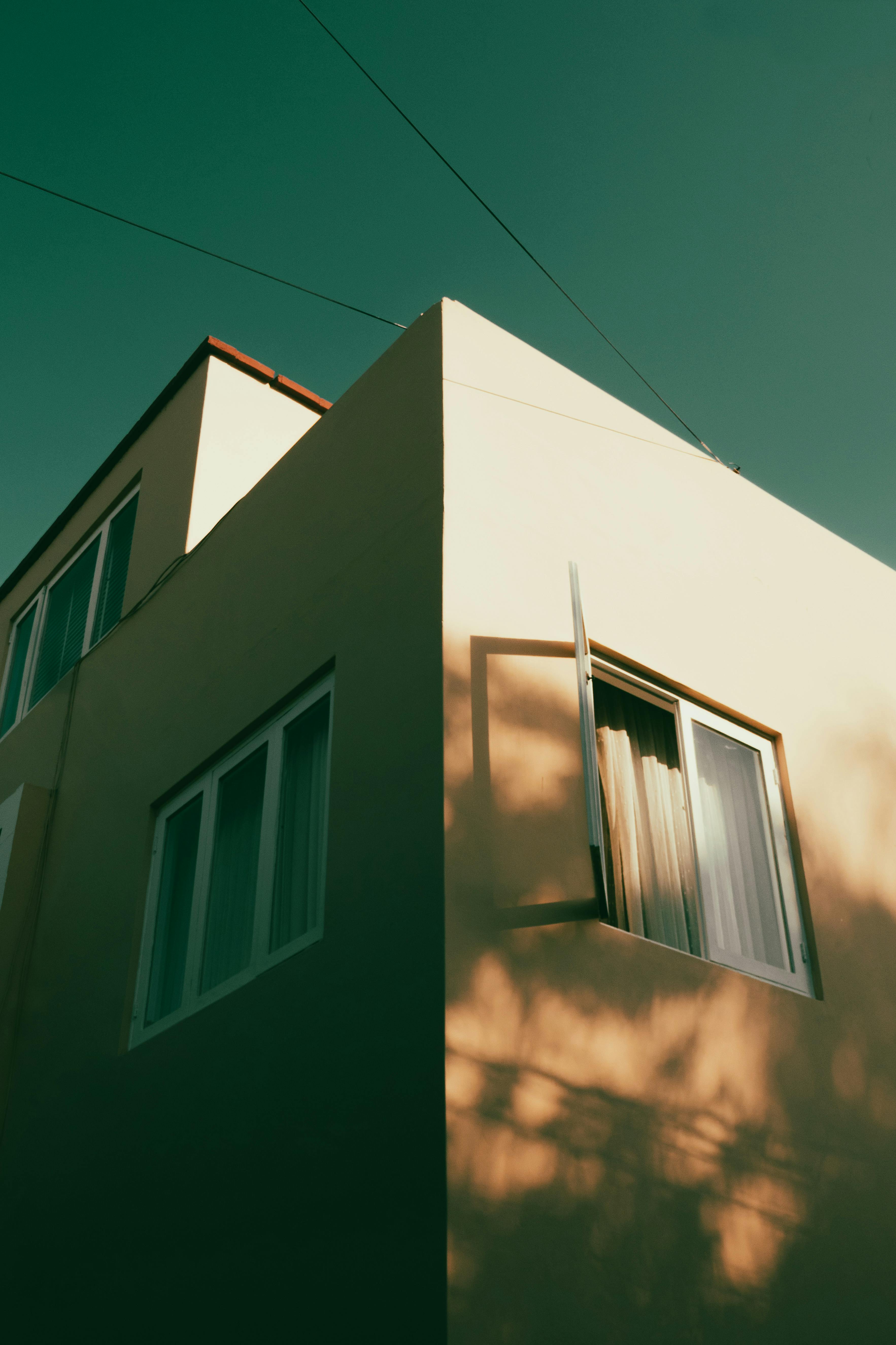 A minimalist architectural view of a building with an open window casting shadows.