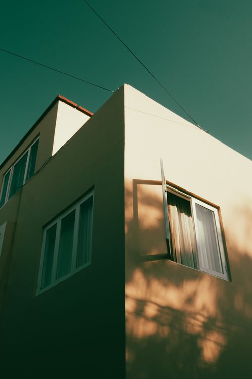 Free A minimalist architectural view of a building with an open window casting shadows. Stock Photo