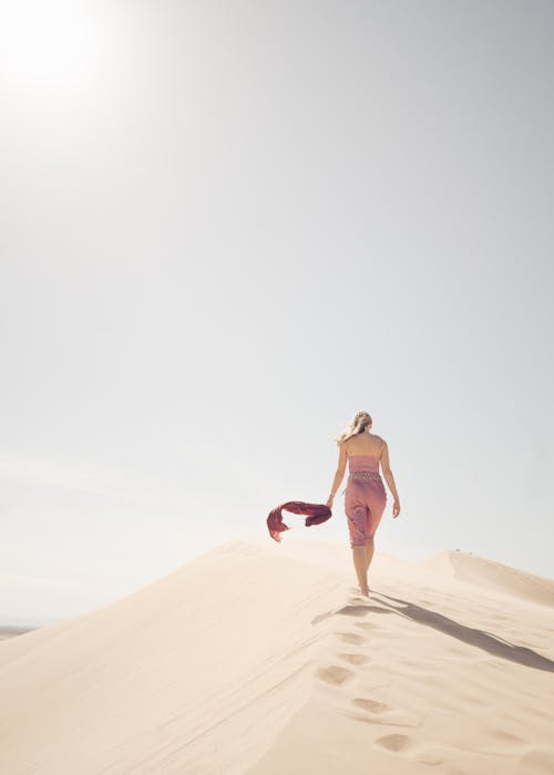 Blonde Woman Walking along Dune Ridge