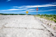 晴朗的蓝天下，空旷的乡村道路旁立着停车和警告标志