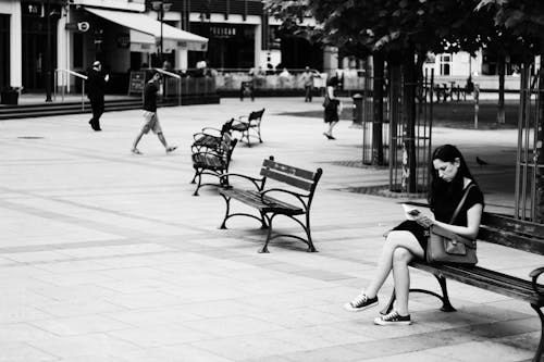 Grijswaardenfotografie Van Een Vrouw Zittend Tijdens Het Lezen Van Een Boek