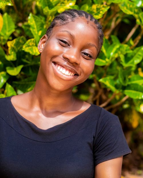Free Close-up portrait of a smiling young woman with braided hair in a natural setting. Stock Photo