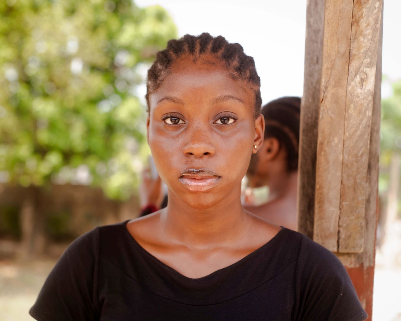 close up portrait of a woman wearing a black shirt with cornrow hairst
