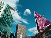 从低角度仰望现代摩天大楼，玻璃外墙映衬着清澈的蓝天