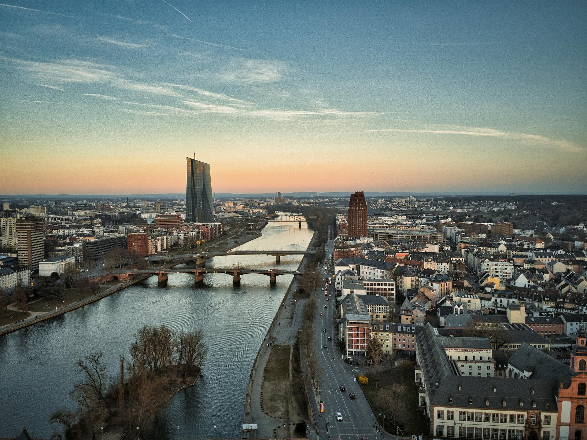 A stunning aerial view of Frankfurt am Main featuring the iconic ECB Tower and the Main River at sunset.