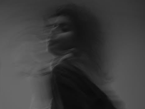 Artistic black and white photograph showcasing a woman's blurred motion in a studio setting.