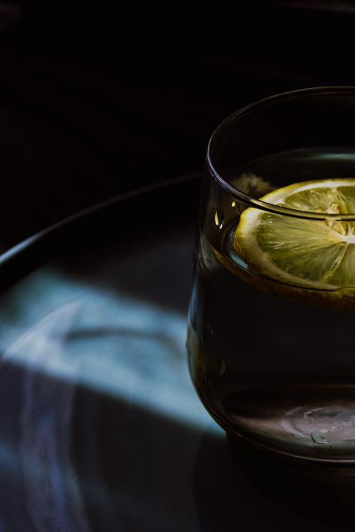 Free Artistic close-up of water with a lemon slice in a glass on a dark background. Stock Photo