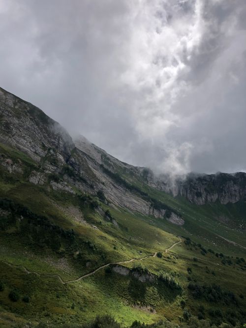 Free A captivating view of a mountainous landscape shrouded in clouds, with a winding path. Stock Photo