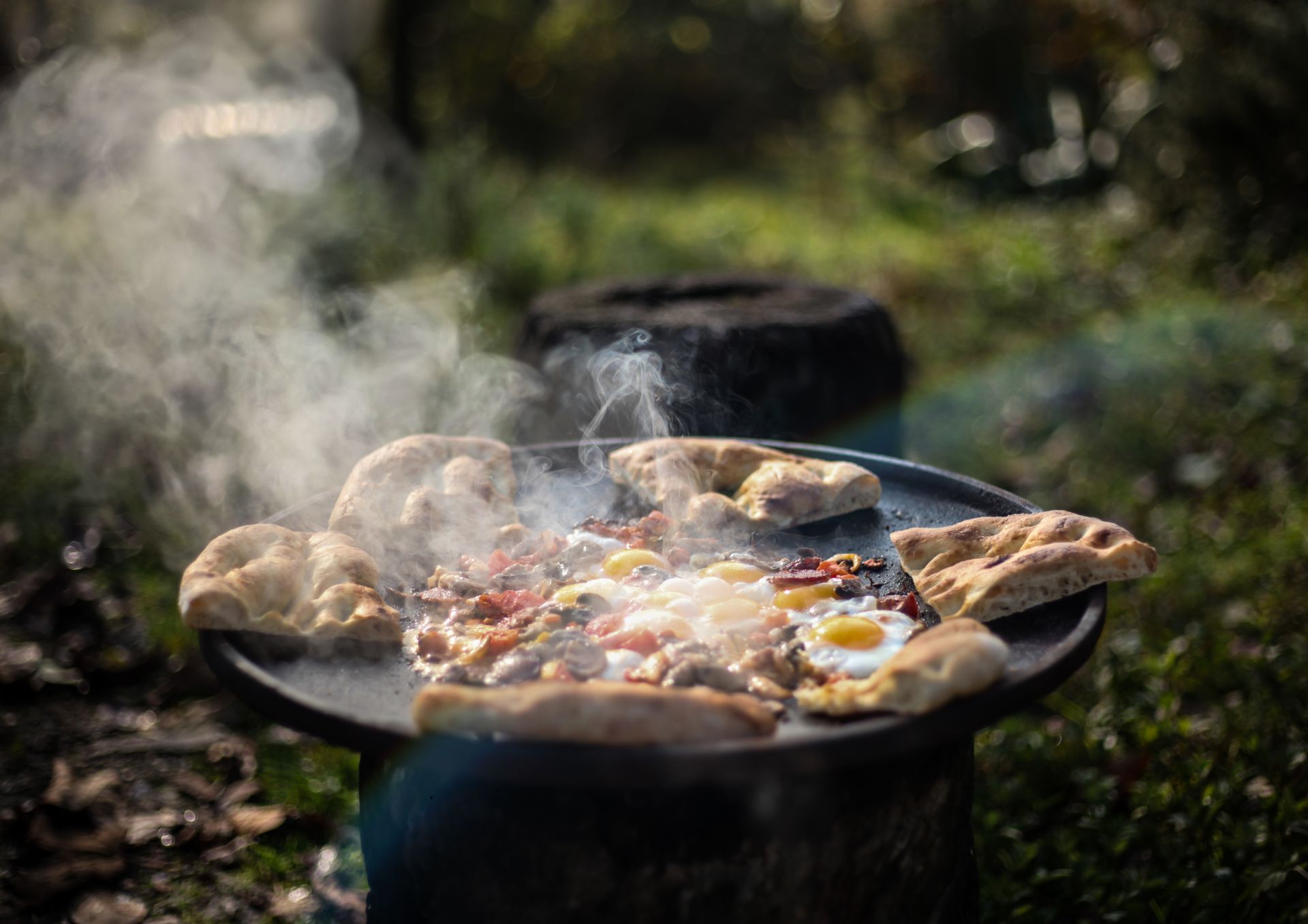 Delicious outdoor cooking scene featuring eggs and flatbread on a cast iron pan with smoke.