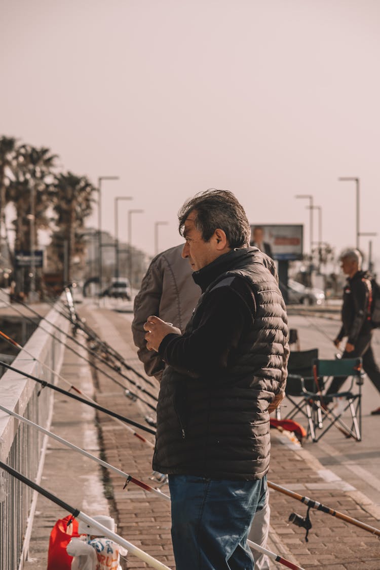 Man Standing Beside Fishing Rods