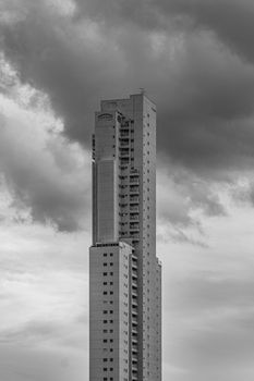 Monochrome image of a tall skyscraper with dramatic clouds.