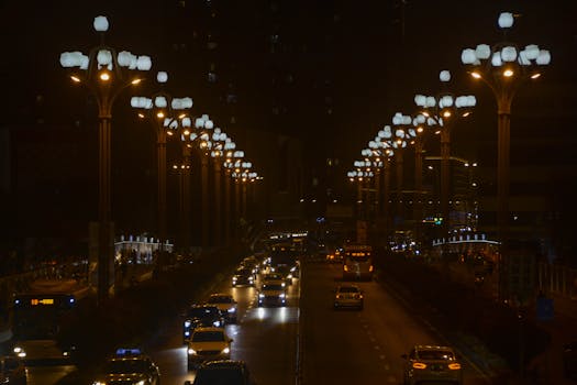Dynamic urban night scene showcasing traffic under illuminated streetlights on a bustling city road.